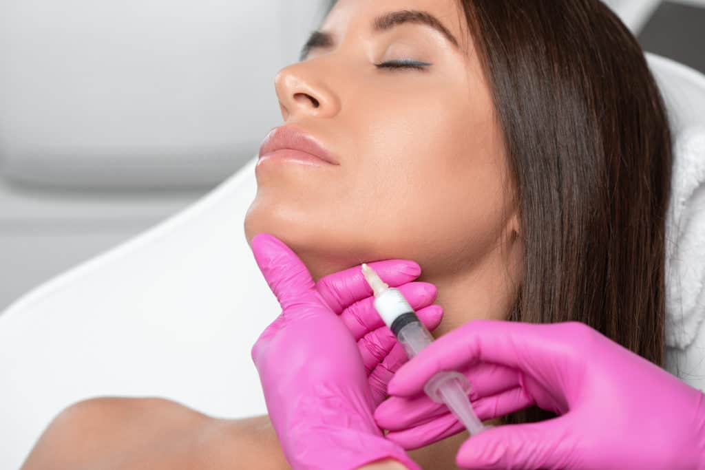 Cosmetologist makes lipolytic injections to burn fat on the chin, cheeks and neck of a woman against double chin by Keybella. Female aesthetic cosmetology in a beauty salon | Elysian Beauty & Wellness in Waycross, GA